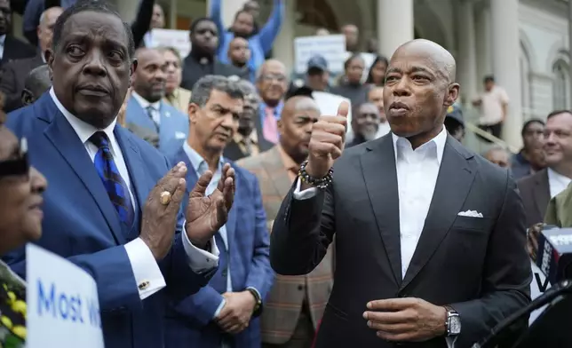 New York City Mayor Eric Adams, right, is surrounded by faith leaders and other supporters during a rally and prayer vigil on the steps of City Hall in New York, Tuesday, Oct. 1, 2024. (AP Photo/Seth Wenig)