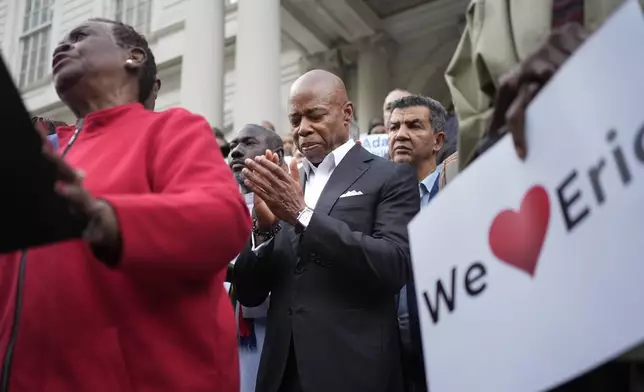 New York City Mayor Eric Adams, center, is surrounded by faith leaders and other supporters during a rally and prayer vigil on the steps of City Hall in New York, Tuesday, Oct. 1, 2024. (AP Photo/Seth Wenig)