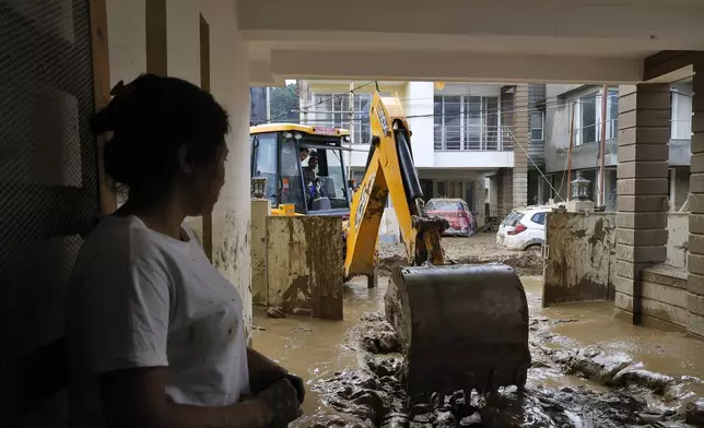 A resident looks on as an earthmover removes mud inside a housing complex in Kathmandu, Nepal, Monday, Sept. 30, 2024 in the aftermath of a flood caused by heavy rains. (AP Photo/Gopen Rai)