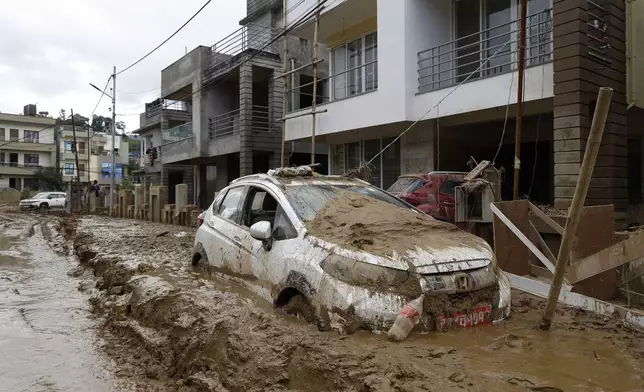 A car parked outside a building is swamped in mud in Kathmandu, Nepal, Monday, Sept. 30, 2024 in the aftermath of a flood caused by heavy rains. (AP Photo/Gopen Rai)