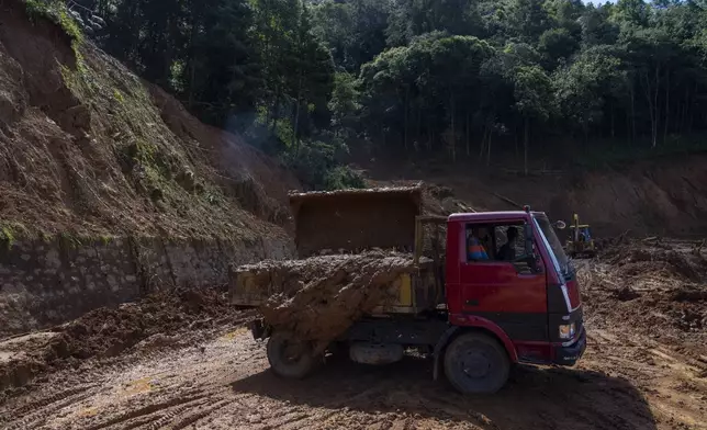 Workers clear mud from a landslide on a road damaged due to heavy rains in Lalitpur, Nepal, on Tuesday, Oct. 1, 2024. (AP Photo/Niranjan Shrestha)