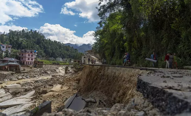 A part of a road is damaged in the floods caused by heavy rains in Lalitpur, Nepal, on Tuesday, Oct. 1, 2024. (AP Photo/Niranjan Shrestha)