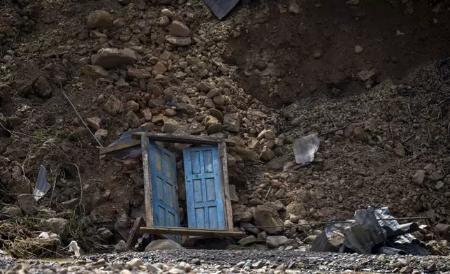 A door from a building damaged in the floods caused by heavy rains lies at the edge of the Nakhu river in Lalitpur, Nepal, on Tuesday, Oct. 1, 2024. (AP Photo/Niranjan Shrestha)