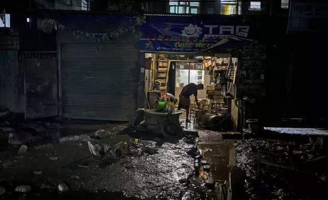 A man removes mud from his shop damaged in the floods caused by heavy rains, in Kathmandu, Nepal, on Tuesday, Oct. 1, 2024. (AP Photo/Niranjan Shrestha)