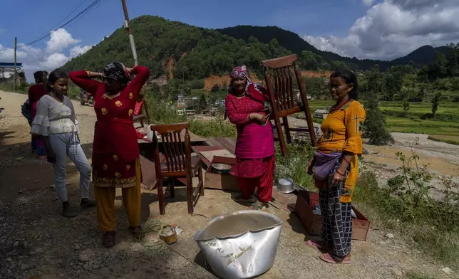 Women salvage their belongings from a house damaged in the floods caused by heavy rains in Lalitpur, Nepal, on Tuesday, Oct. 1, 2024. (AP Photo/Niranjan Shrestha)