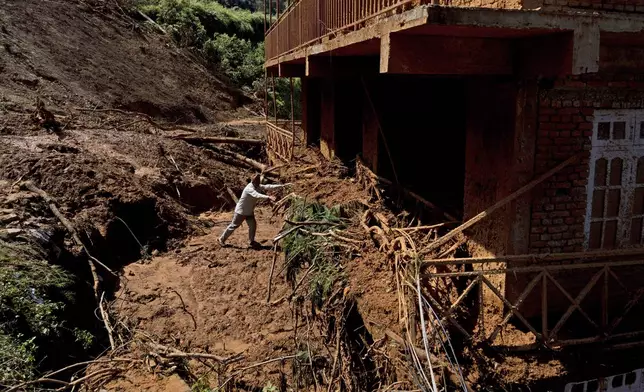 A man clears the wreckage from his house damaged in the floods caused by heavy rains in Lalitpur, Nepal, on Tuesday, Oct. 1, 2024. (AP Photo/Niranjan Shrestha)