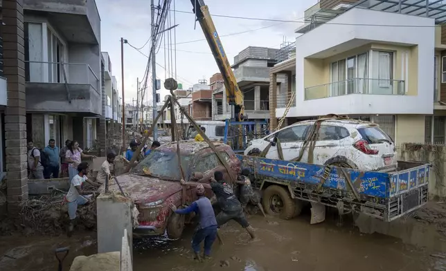 A crew uses cranes to lift vehicles out of the mud after flooding in the Nakhu river caused by heavy rains in Lalitpur, Nepal, on Tuesday, Oct. 1, 2024. (AP Photo/Niranjan Shrestha)