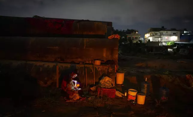 A man lives with his child in an open area after his house was swept away by the flooding Bagmati River, in Kathmandu, Nepal, on Tuesday, Oct. 1, 2024. (AP Photo/Niranjan Shrestha)