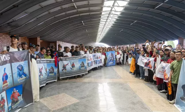 Friends and family of Nepalese mountaineers, including Nima Rinji Sherpa, the youngest person to scale all the world’s 14 highest peaks, gather at Tribhuvan International Airport in Kathmandu, Nepal, Monday, Oct. 14, 2024. (AP Photo/Niranjan Shrestha)