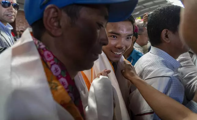 Friends and family of Nepalese mountaineers welcome Nima Rinji Sherpa, the youngest person to scale all the world’s 14 highest peaks, upon his arrival at Tribhuvan International Airport in Kathmandu, Nepal, Monday, Oct. 14, 2024. (AP Photo/Niranjan Shrestha)