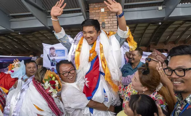 Minima Sherpa, father of 18-year-old Nima Rinji Sherpa, the youngest person to scale all the world’s 14 highest peaks, celebrates with his family upon his son's arrival at Tribhuvan International Airport in Kathmandu, Nepal, Monday, Oct. 14, 2024. (AP Photo/Niranjan Shrestha)