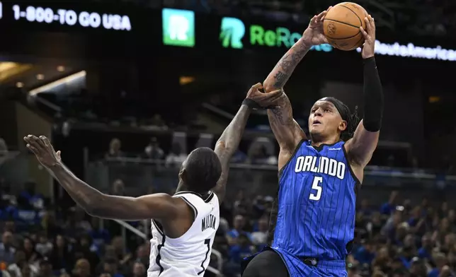 Orlando Magic forward Paolo Banchero (5) is fouled by Brooklyn Nets guard Shake Milton (7) while going up to shoot during the second half of an NBA basketball game, Friday, Oct. 25, 2024, in Orlando, Fla. (AP Photo/Phelan M. Ebenhack)