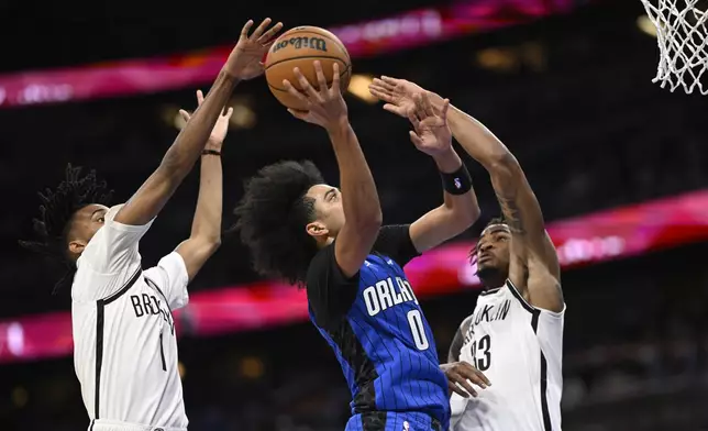 Orlando Magic guard Anthony Black (0) goes up to shoot as Brooklyn Nets forward Ziaire Williams (1) and center Nic Claxton (33) defend during the first half of an NBA basketball game Friday, Oct. 25, 2024, in Orlando, Fla. (AP Photo/Phelan M. Ebenhack)