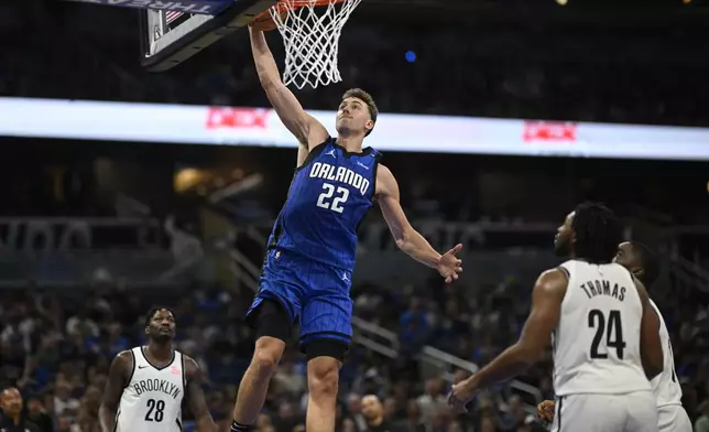 Orlando Magic forward Franz Wagner (22) dunks between Brooklyn Nets forward Dorian Finney-Smith (28) and guard Cam Thomas (24) during the second half of an NBA basketball game, Friday, Oct. 25, 2024, in Orlando, Fla. (AP Photo/Phelan M. Ebenhack)