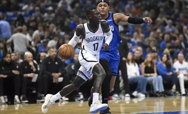 Brooklyn Nets guard Dennis Schroder (17) drives past Orlando Magic forward Paolo Banchero during the first half of an NBA basketball game Friday, Oct. 25, 2024, in Orlando, Fla. (AP Photo/Phelan M. Ebenhack)