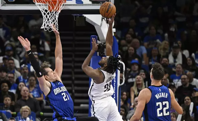 Brooklyn Nets guard Cam Thomas (24) shoots between Orlando Magic center Moritz Wagner (21) and forward Franz Wagner (22) during the second half of an NBA basketball game, Friday, Oct. 25, 2024, in Orlando, Fla. (AP Photo/Phelan M. Ebenhack)