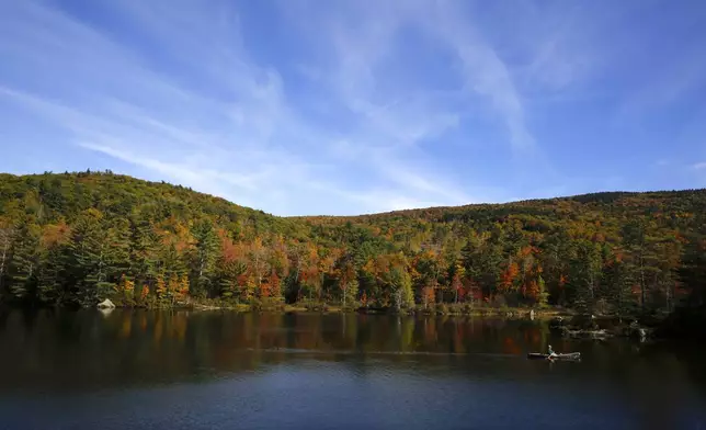 A fly fisherman paddles on a pond as fall foliage begins to show color in Campton, N.H., Sunday, Oct. 6, 2024. (AP Photo/Caleb Jones)