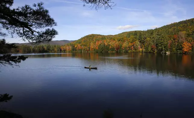 A fly fisherman paddles on a pond as fall foliage begins to show color in Campton, N.H., Sunday, Oct. 6, 2024. (AP Photo/Caleb Jones)