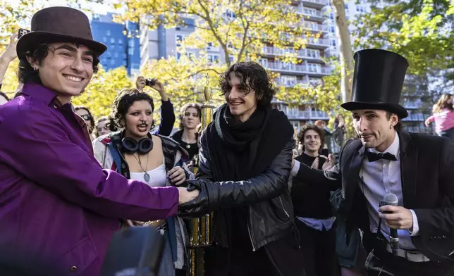 Finalists Miles Mitchell, left and Zander Dueve, center, shake hands at the Timothee Chalamet lookalike contest near Washington Square Park, Sunday, Oct. 27, 2024, in New York. (AP Photo/Stefan Jeremiah)