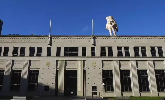 A 16-foot- ( almost 5 meters ) tall hand sculpture named Quasi stands perched on its fingertips atop the roof of an art gallery in Wellington, New Zealand, Wednesday, Oct. 30, 2024. (AP photo/Charlotte Graham-McLay)