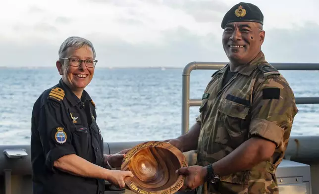 In this undated photo provided by the New Zealand Defence Force, Lieutenant Commander Tala Mafile'o of the Royal Tongan Navy presents Commander Yvonne Gray, left, with a carved wooden bowl as a memento of the RNZN's participation in the 50th Anniversary Fleet Review. (New Zealand Defence Force via AP)