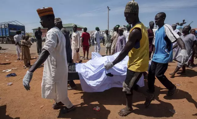 People carry the body of a victim of a tanker explosion before a funeral in Majiya town, Nigeria, Wednesday, Oct. 16, 2024. (AP Photo/Sani Maikatanga)