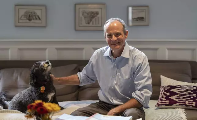 Economist Simon Johnson poses for a photograph with his dog Zoya after winning the Nobel memorial prize in economics with Daron Acemoglu and James A. Robinson, at his home in Washington, Monday, Oct. 14, 2024. (AP Photo/Ben Curtis)