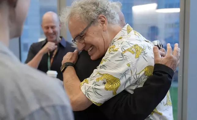 Victor Ambros, 2024 Nobel Prize winner in physiology or medicine, and professor of natural science at the University of Massachusetts Medical School, right, hugs collegue Allan Jacobson, at the school, in Worcester, Mass. Monday, Oct. 7, 2024. (AP Photo/Steven Senne)