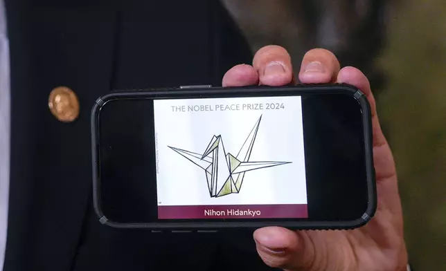 The head of the Nobel Committee, Jorgen Watne Frydnes, shows the logo of the Japanese organization Nihon Hidankyo, the winner of the Nobel Peace Prize for 2024, at the Nobel Institute in Oslo, Norway, Friday, Oct. 11, 2024. The Nobel Peace Prize was awarded Friday to Nihon Hidankyo, a Japanese organization of survivors of the U.S. atomic bombings of Hiroshima and Nagasaki, for its activism against nuclear weapons. (Javad Parsa/NTB Scanpix via AP)