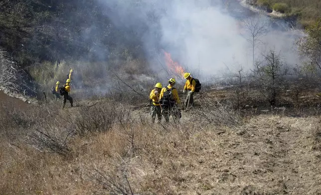 In this photo provided by the U.S. Army National Guard, North Dakota National Guard soldiers and airmen work with the Department of Emergency Services to build a handline and conduct a controlled burn to prevent the further spread of a wildfire in Mandaree, N.D., Sunday, Oct. 6, 2024. (Staff Sgt. Samuel J. Kroll/U.S. Army National Guard via AP)