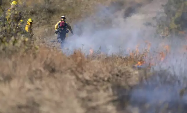 In this photo provided by the U.S. Army National Guard, North Dakota National Guard soldiers and airmen work with the Department of Emergency Services to build a handline and conduct a controlled burn to prevent the further spread of a wildfire in Mandaree, N.D., Sunday, Oct. 6, 2024. (Staff Sgt. Samuel J. Kroll/U.S. Army National Guard via AP)