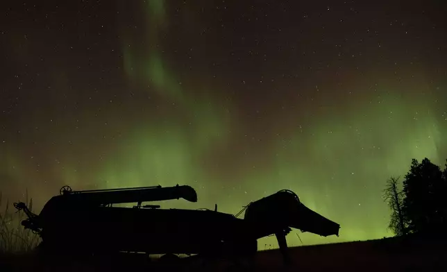 An aurora borealis, also known as the northern lights, is seen in the night sky above a wheat threshing machine from the late 19th century on Thursday, Oct. 10, 2024, in Moscow, Idaho. (AP Photo/Ted S. Warren)