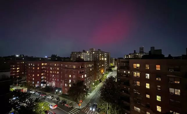 An aurora borealis, also known as the northern lights, glows in the night sky above apartment buildings in the Queens borough of New York, Thursday, Oct. 10, 2024. (AP Photo/Daniel P. Derella)