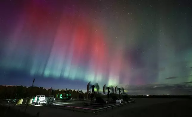 An aurora borealis, also known as the northern lights, makes an appearance over pumpjacks as they draw out oil and gas from well heads near Cremona, Alberta, Thursday, Oct. 10, 2024. (Jeff McIntosh/The Canadian Press via AP)