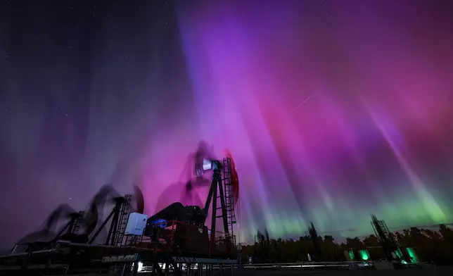 An aurora borealis, also known as the northern lights, makes an appearance over pumpjacks as they draw out oil and gas from well heads near Cremona, Alberta, Thursday, Oct. 10, 2024. (Jeff McIntosh/The Canadian Press via AP)