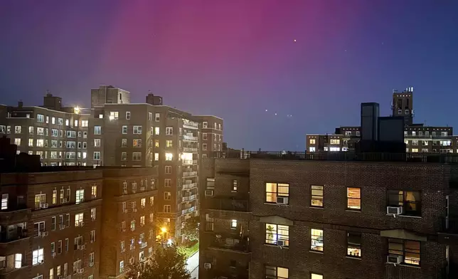 An aurora borealis, also known as the northern lights, glows in the night sky above apartment buildings in the Queens borough of New York, Thursday, Oct. 10, 2024. (AP Photo/Daniel P. Derella)