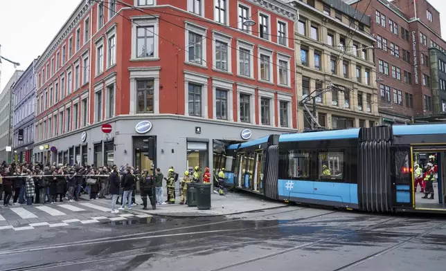 People and rescuers gather at the scene where a tram derailed and crashed into a building in downtown Oslo, Norway, Tuesday Oct. 29, 2024. (Terje Pedersen/NTB Scanpix via AP)