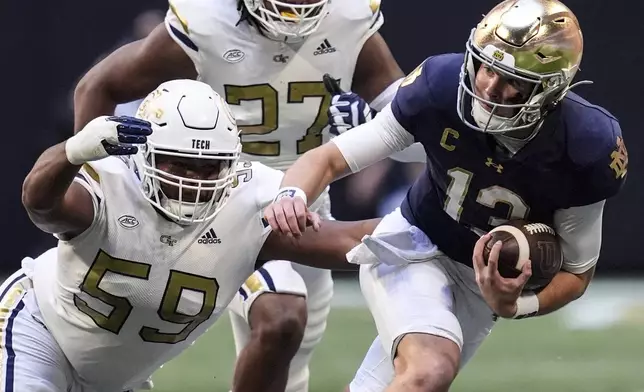 Notre Dame quarterback Riley Leonard (13) runs against Georgia Tech defensive lineman Thomas Gore (59) during the first half of an NCAA college football game, Saturday, Oct. 19, 2024, in Atlanta. (AP Photo/Mike Stewart)