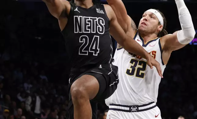 Brooklyn Nets' Cam Thomas (24) goes to the basket against Denver Nuggets' Aaron Gordon (32) during the first quarter of an NBA basketball game, Tuesday, Oct. 29, 2024, in New York. (AP Photo/Jason DeCrow)