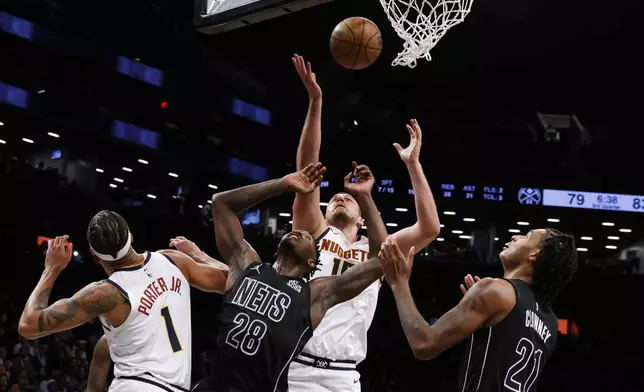 Denver Nuggets' Nikola Jokic (15), of Serbia, goes up for a rebound against Brooklyn Nets' Dorian Finney-Smith (28) and Noah Clowney (21) during the third quarter of an NBA basketball game Tuesday, Oct. 29, 2024, in New York. (AP Photo/Jason DeCrow)