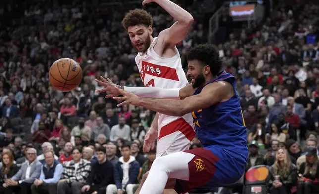 Denver Nuggets guard Jamal Murray, right, passes the ball as Toronto Raptors forward Jamison Battle, left, attempts to screen him during second-half NBA basketball game action in Toronto, Monday, Oct. 28, 2024. (Nathan Denette/The Canadian Press via AP)