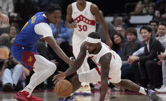 Toronto Raptors guard Jamal Shead, right, and Denver Nuggets forward Peyton Watson, left, vie for the ball during second-half NBA basketball game action in Toronto, Monday, Oct. 28, 2024. (Nathan Denette/The Canadian Press via AP)