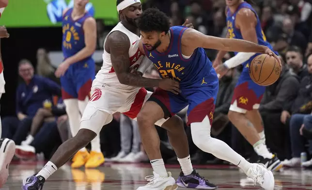 Denver Nuggets guard Jamal Murray (27) drives into Toronto Raptors guard Jamal Shead, left, during first-half NBA basketball game action in Toronto, Monday, Oct. 28, 2024. (Nathan Denette/The Canadian Press via AP)