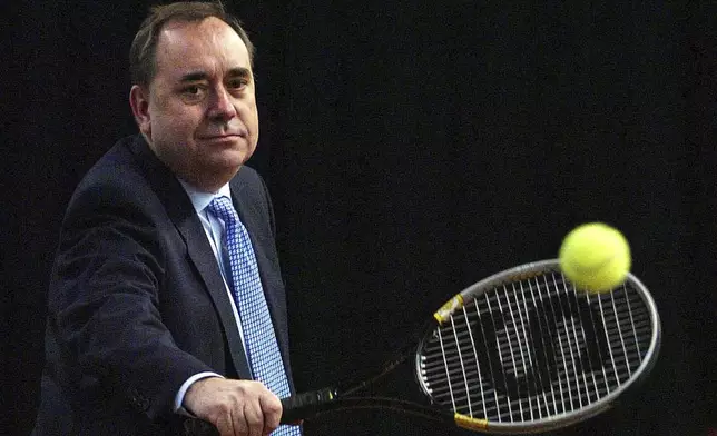 FILE - Alex Salmond takes some tennis shots during a tour of Stirling University's new sports facilities on April 27, 2007. (David Cheskin/PA via AP)