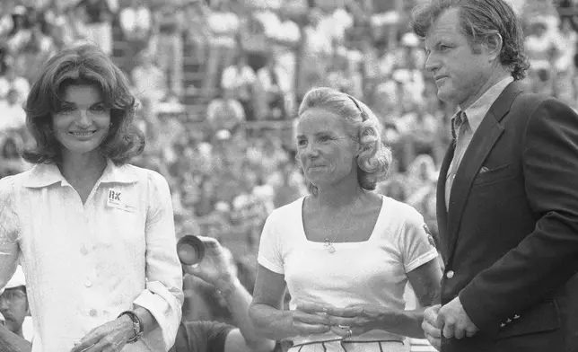 FILE - Mrs. Ethel Kennedy, center, wife of the late Sen. Robert F. Kennedy, stands with her sister-in-law, Mrs. Jacqueline Kennedy Onassis, and brother-in-law Senator Edward Kennedy, at the Robert F. Kennedy Pro-Celebrity Tennis Tournament at New York's Forest Hills Stadium in Queens County, on Aug. 23, 1975. (AP Photo/Suzanne Vlamis, File)