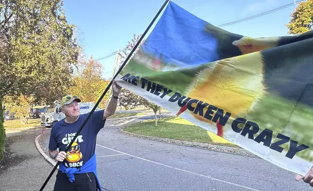 Supporters of Richard Schiffer Jr., who faces witness intimidation and other charges related to the Karen Read case, display a flag outside Stoughton District Court before Schiffer's arraignment, Wednesday, Oct. 23, 2024 in Stoughton, Mass. (AP Photo/Michael Casey)