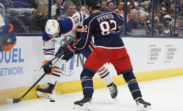 Edmonton Oilers' Troy Stecher, left, and Columbus Blue Jackets' Mikael Pyyhtia fight for the puck during the second period of an NHL hockey game Monday, Oct. 28, 2024, in Columbus, Ohio. (AP Photo/Jay LaPrete)