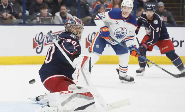 Columbus Blue Jackets' Elvis Merzlikins, left, makes a save against the Edmonton Oilers during the third period of an NHL hockey game Monday, Oct. 28, 2024, in Columbus, Ohio. (AP Photo/Jay LaPrete)