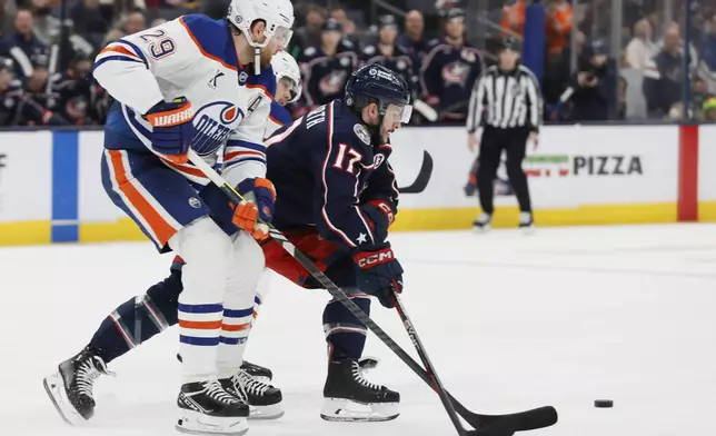 Columbus Blue Jackets' Justin Danforth, right, clears the puck past Edmonton Oilers' Leon Draisaitl during the second period of an NHL hockey game Monday, Oct. 28, 2024, in Columbus, Ohio. (AP Photo/Jay LaPrete)