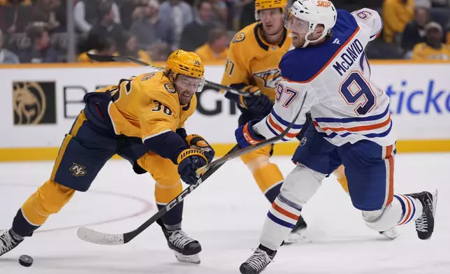 Edmonton Oilers center Connor McDavid (97) shoots the puck past Nashville Predators left wing Cole Smith (36) during the third period of an NHL hockey game Thursday, Oct. 17, 2024, in Nashville, Tenn. (AP Photo/George Walker IV)